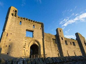 A large stone castle with a central archway and two towers. - The Round House (Leyburn)