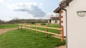 A fenced outdoor area with a building in the background. - Broom Cottage (Sidmouth)