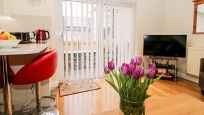 Un salon moderne comprenant un coin repas, un téléviseur et un vase de tulipes.