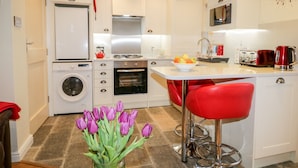 Une cuisine moderne avec des meubles blancs, un four encastré, un lave-linge et un évier.
