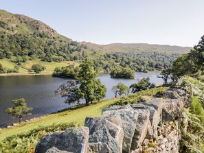 A stone wall with a view of a lake and hills. - Church View (Ambleside)