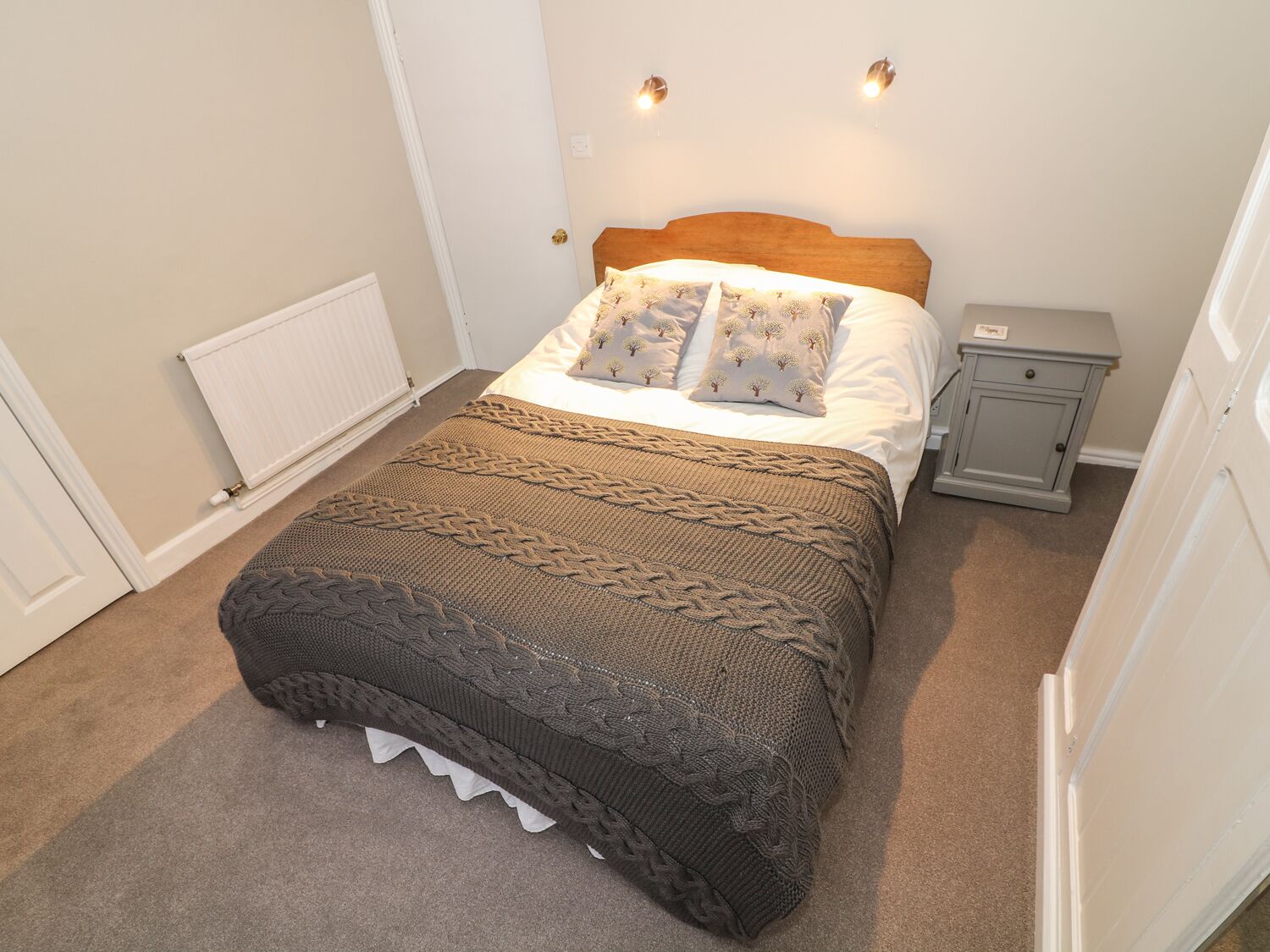 Une chambre à coucher bien rangée, avec un lit, une table de chevet et une petite table d’appoint.