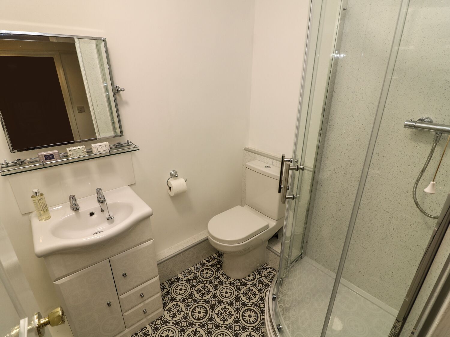 Une salle de bain équipée d’un lavabo, de toilettes et d’une douche à parois de verre.