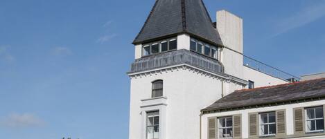 A white building with a black roof and a tower with a balcony.