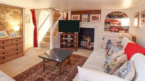 Ein Wohnzimmer mit einer Couch, einem Couchtisch, einem Fernseher, einem Kamin und einer Treppe.