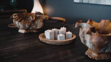 A wooden table with a decorative bowl containing six white candles.