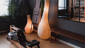 A modern room with a rowing machine, large vases, and a mirror on the wall.
