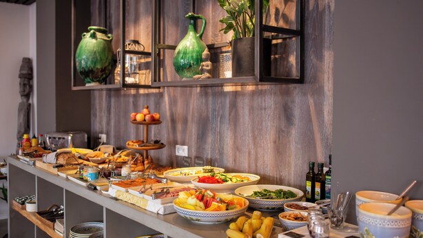 A buffet with various dishes and drinks, including fruits, salads, and bread.