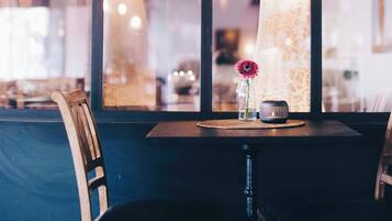 A restaurant interior with a table set for two, a vase with a flower, and a decorative item on the table.