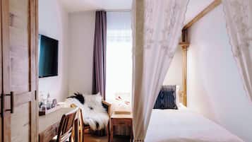 Ein Schlafzimmer mit einem Bett, einem Schreibtisch, einem Sessel, einem Fernseher und einem Vorhangfenster.