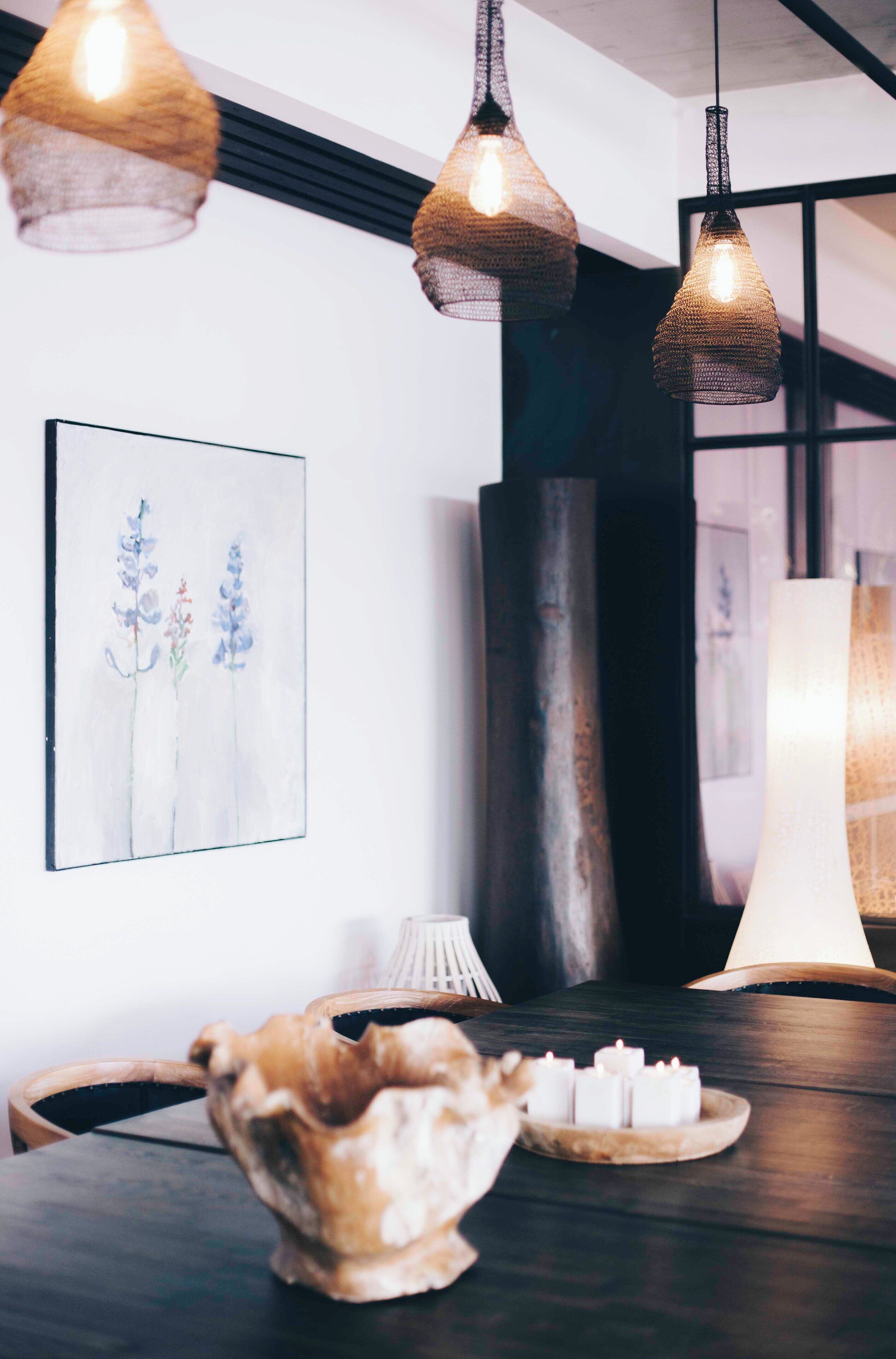 A dining area with a dark wooden table, a white vase, and a candle holder.