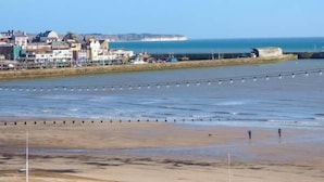 Un pueblo costero con edificios a lo largo de la costa, una playa de arena y una vista despejada del mar.