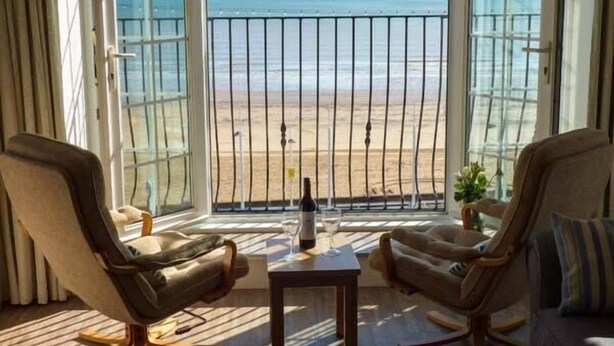Habitación con dos sillones mirando un balcón con vista a la playa y al océano.