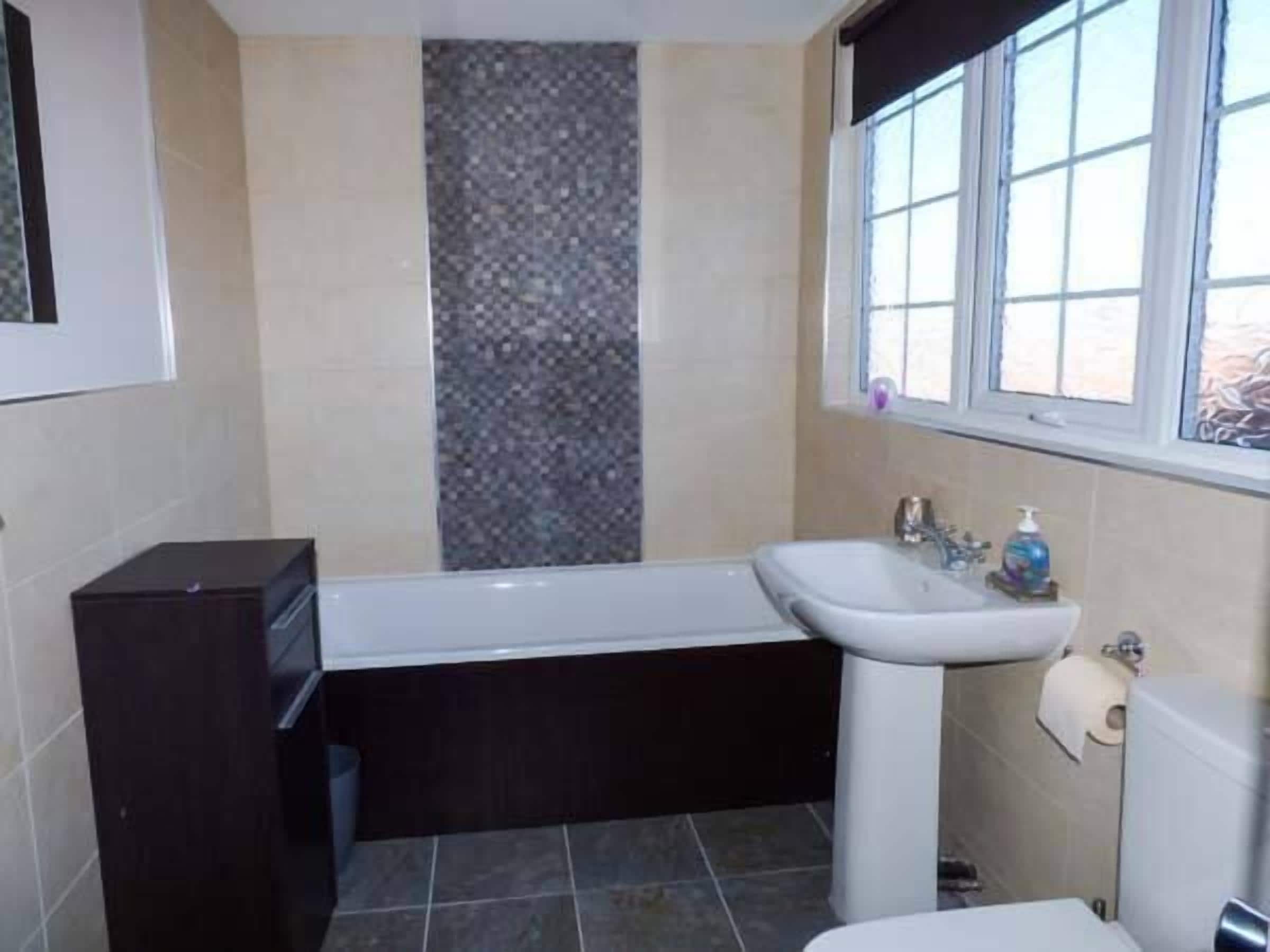 Un baño con bañera, lavamanos e inodoro.