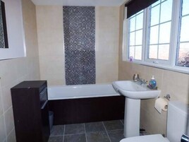 Un baño con bañera, lavamanos e inodoro.
