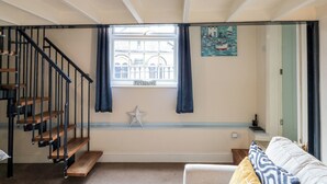 Een kamer met een trap, een raam met een ‘ROKEN VERBODEN’ bord en een ster decoratie, plus een schilderij van een boot.