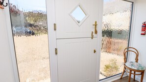 A white door with a small window, a brass handle, and a keyhole. - Stable Cottage (Newport)