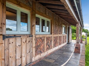 A wooden building with large windows and a brick pathway. - The Lodge (Chester)