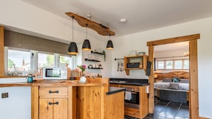 A modern kitchen with wooden cabinetry, a central island, and pendant lighting. - The Lodge (Chester)