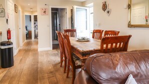 Un coin repas avec une table et des chaises en bois, un canapé en cuir et un grand miroir au mur.
