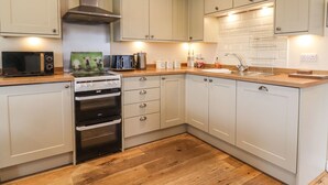 Une cuisine moderne avec des meubles blancs, un four à micro-ondes, une cuisinière et un évier.