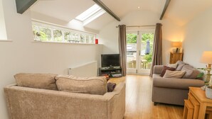 A living room with two sofas, a TV, and a wooden floor. - The Potting Shed (Carnforth)