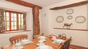 A dining room with a wooden table set for four, surrounded by wooden chairs. - The Dairy (Taunton)