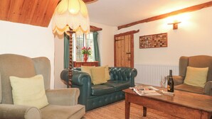 A cozy living room with a green sofa, a wooden coffee table, and a lamp. - The Dairy (Taunton)