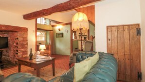 A cozy living room with a leather sofa, a wooden coffee table, and a stone fireplace. - The Dairy (Taunton)