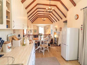 Enjoy meals in this spacious kitchen with a high ceiling, dining table, and modern appliances.