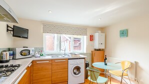 A compact kitchen with a washing machine, microwave, and sink. - Mermaid Cottage (Whitby)