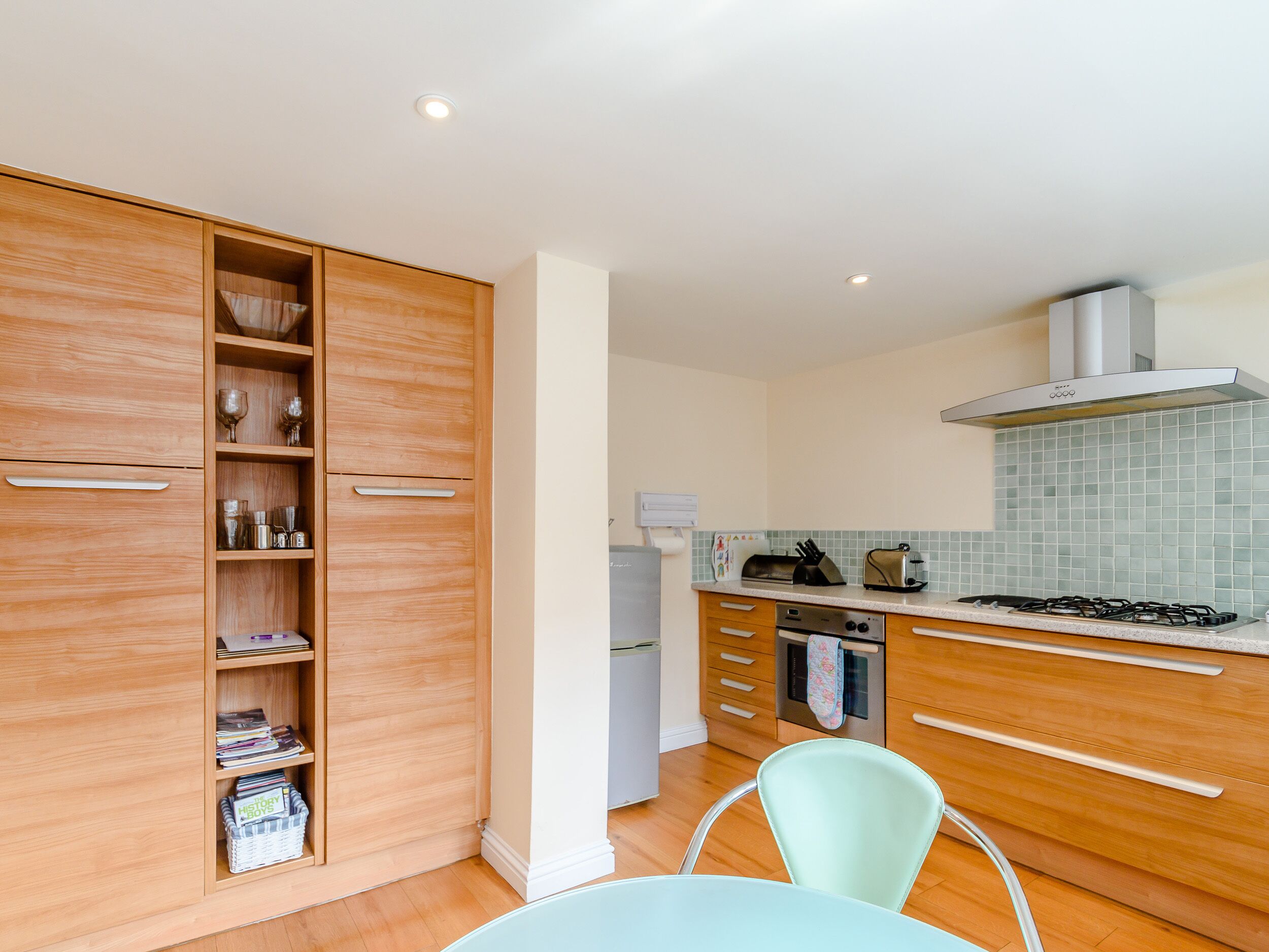 A modern kitchen with wooden cabinets, a gas stove, and a dining area with a table and chairs.