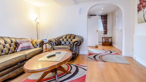 A modern living room with a leather sofa, a wooden coffee table, and a patterned rug. - Mermaid Cottage (Whitby)