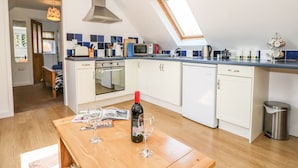 Una cocina moderna con armarios blancos, una mesa de comedor de madera y un tragaluz.