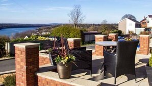An outdoor patio area with brick walls, a table, and chairs. - Crud yr Awel (Y Felinheli)
