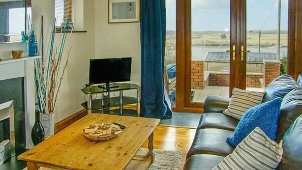 A living room with a wooden coffee table, a leather sofa, and a television on a stand. - Crud yr Awel (Y Felinheli)