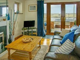 A living room with a wooden coffee table, a leather sofa, and a television on a stand.