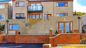 A two-story house with a stone facade, multiple windows, and a brick entrance. - Crud yr Awel (Y Felinheli)