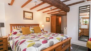 Une chambre à coucher avec un lit en bois, une table de chevet, une lampe et un grand miroir.
