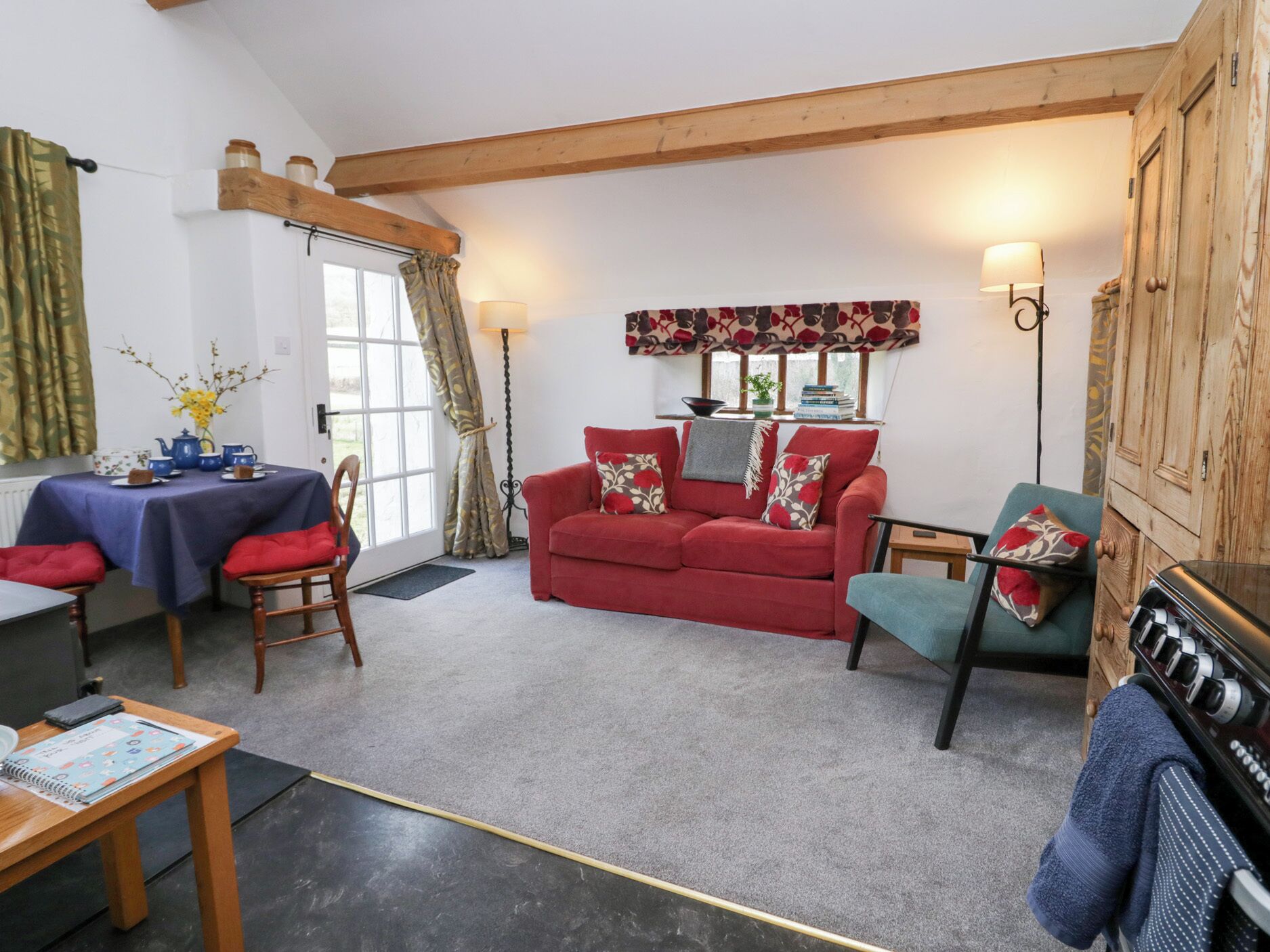 A cozy living room with a red sofa, a wooden table with a blue tablecloth, and a fireplace.