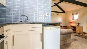 A kitchen with a blue tiled backsplash, a white refrigerator, and a wooden cabinet. - The Granary (Henfield)