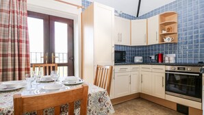 A kitchen with white cabinets, a microwave, a toaster, and a red mug on the counter. - The Granary (Henfield)