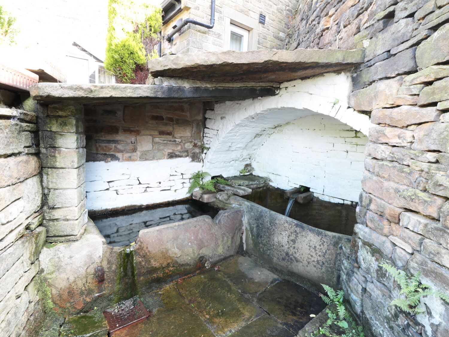 A stone well with a wooden structure above it, surrounded by stone walls.