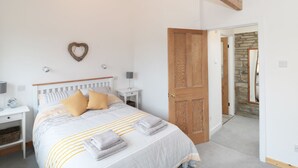 Une chambre à coucher avec un lit, des tables de chevet, un élément de décoration murale en forme de cœur et une porte en bois.