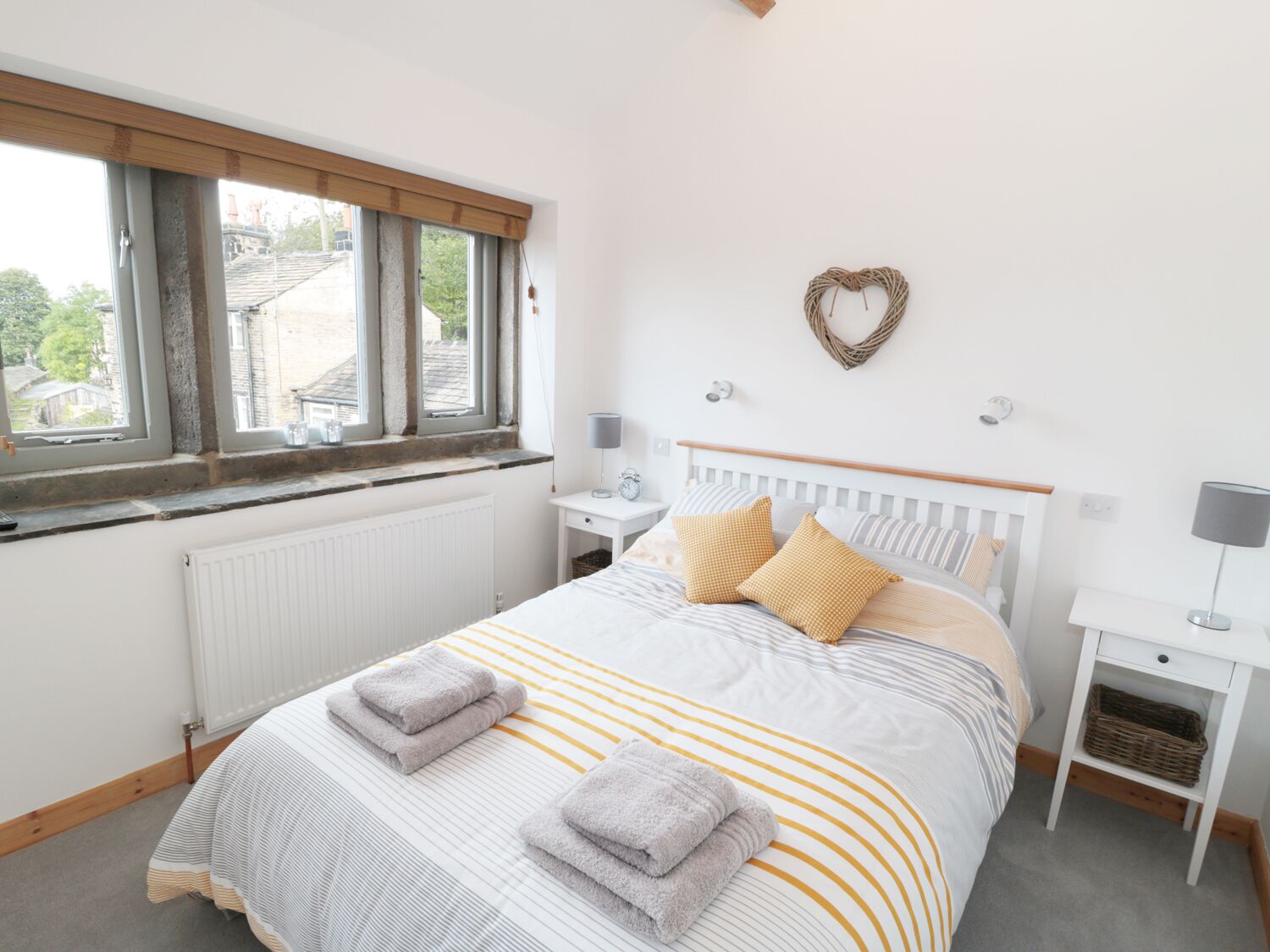 Ein Schlafzimmer mit einem Bett, zwei Nachttischen, einem Fenster und einer Wandleuchte.