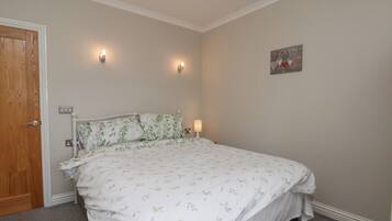 A bedroom with a bed, two wall-mounted lights, a door, and a small decorative item on the wall.
