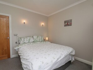 Une chambre à coucher avec un lit, deux lampes fixées au mur, une porte et un petit objet décoratif accroché au mur.