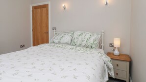 A bedroom with a bed, bedside table, lamp, and a door. - Beacon (Saltburn-by-the-Sea)