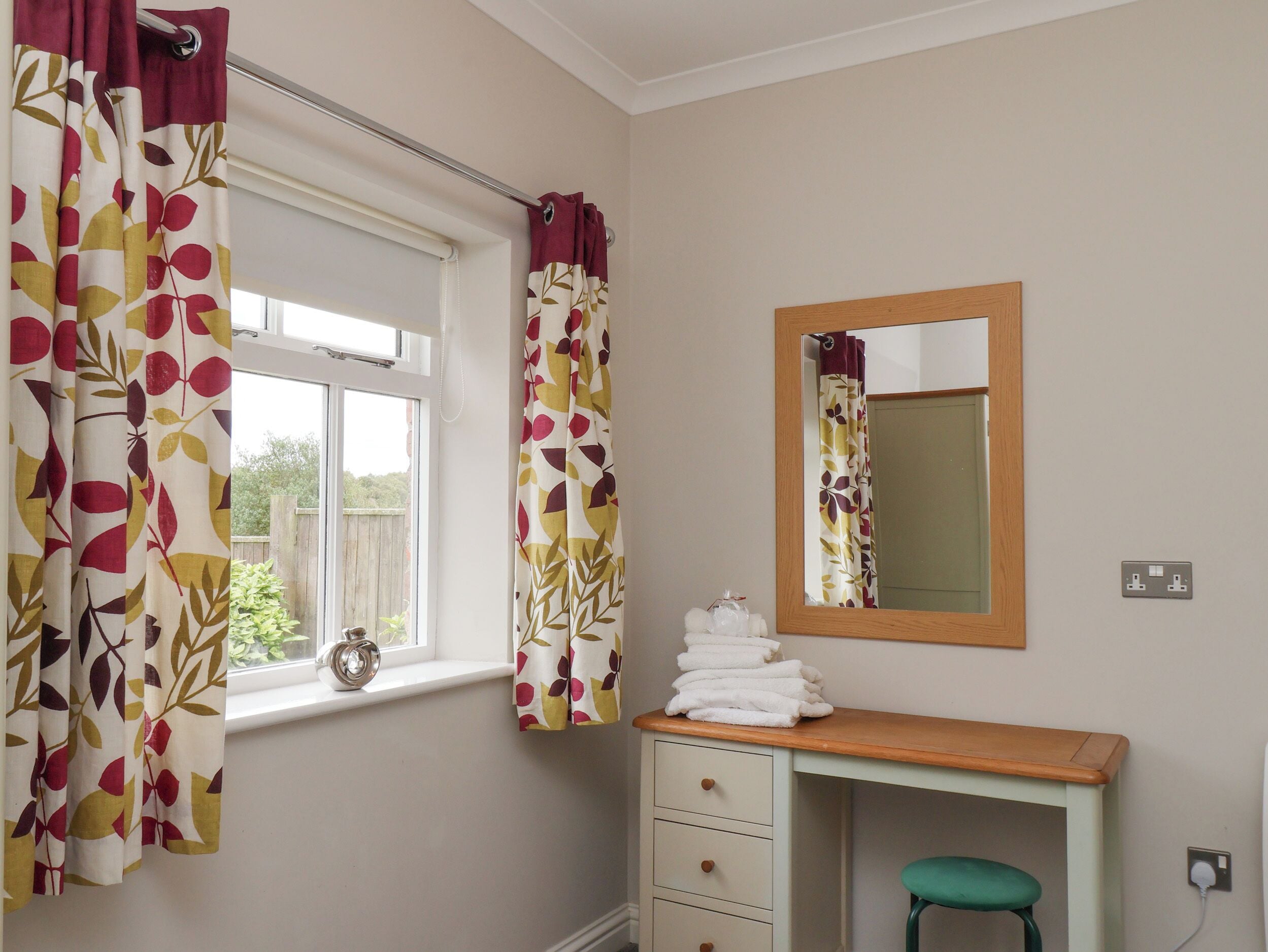 A bathroom with a window, a mirror, a sink, and a towel rack.