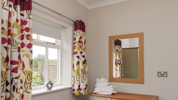 A bathroom with a window, a mirror, a sink, and a towel rack. - Beacon (Saltburn-by-the-Sea)